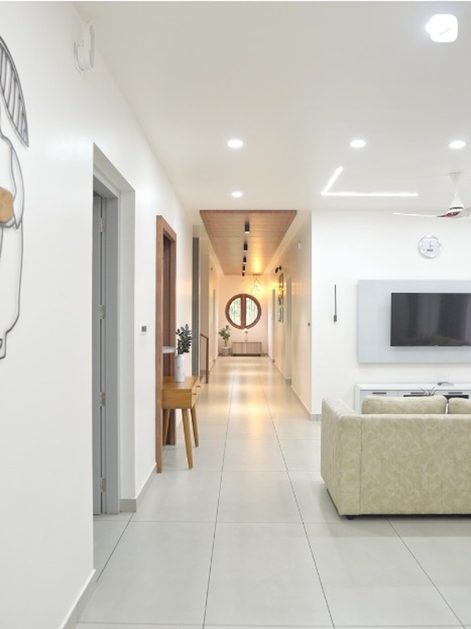 Bright D'Casa Homes corridor with recessed lighting, wooden doors and large-format floor tiles